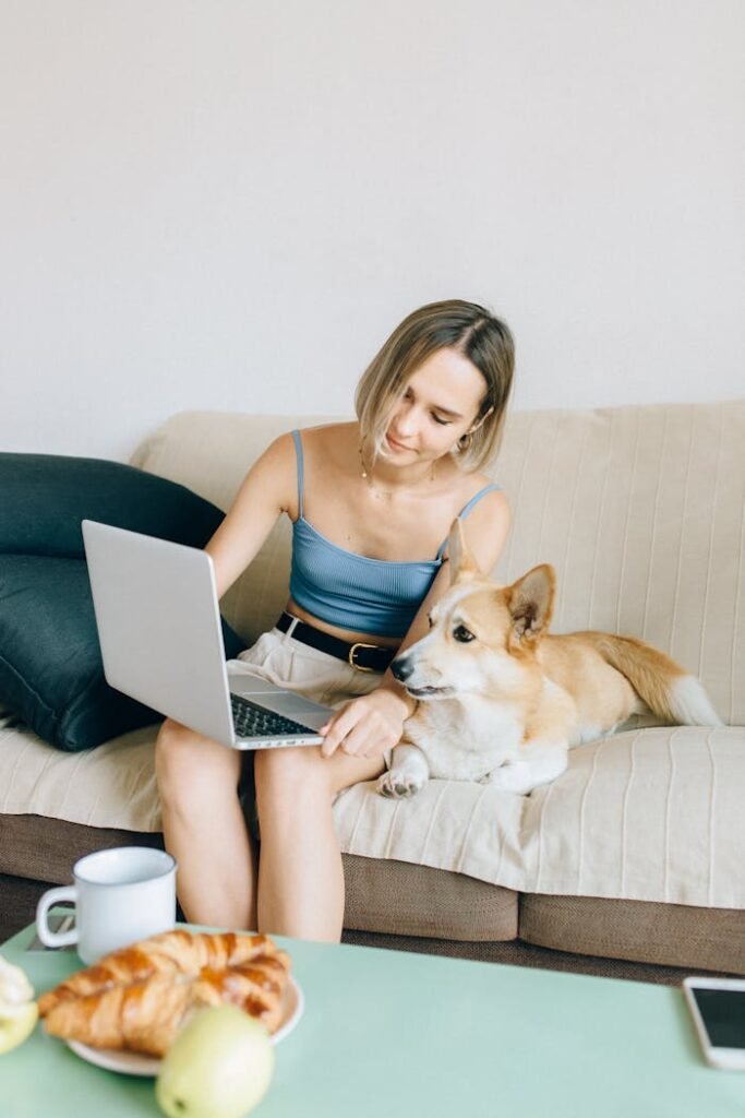 Woman in Blue Tank Top Sitting on Couch Using Macbook